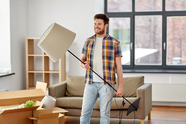 Happy man with floor lamp moving to new home — Stock Photo, Image