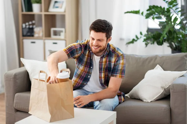 Smiling man unpacking takeaway food at home — Stock Photo, Image