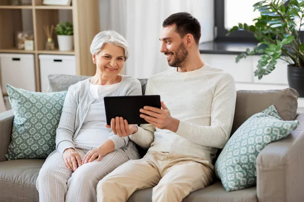 Oude moeder en volwassen zoon met tablet pc thuis — Stockfoto