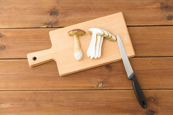 Cogumelos comestíveis, faca de cozinha e tábua de corte — Fotografia de Stock