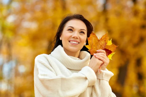 Heureuse jeune femme avec des feuilles d'érable dans le parc d'automne — Photo