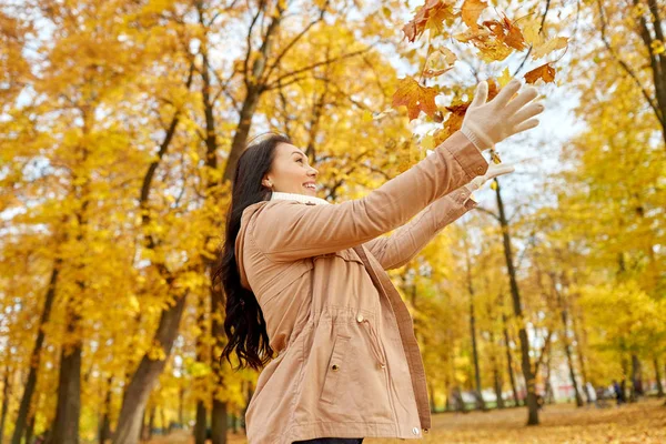 Lycklig kvinna ha kul med löv i höstparken — Stockfoto