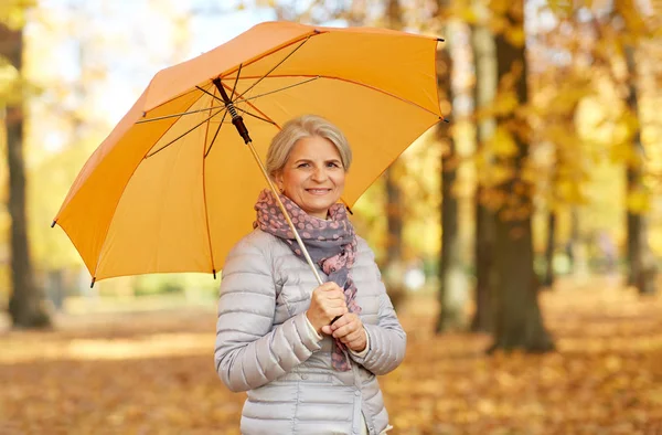 Sonbahar parkında şemsiyesi olan mutlu yaşlı kadın. — Stok fotoğraf