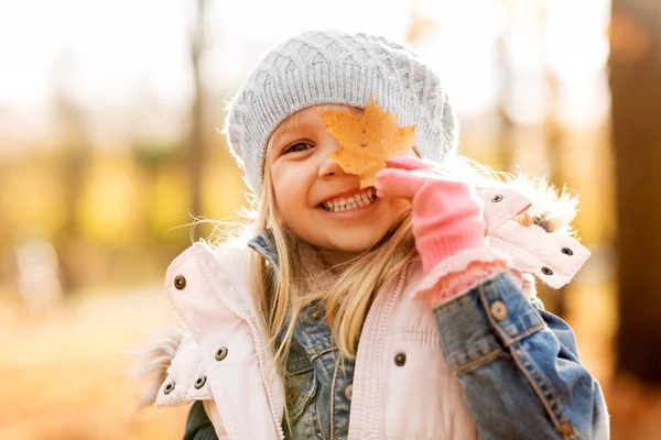 Šťastná holčička s javorovým listem v podzimním parku — Stock fotografie