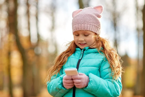 Девушка со смартфоном в осеннем парке — стоковое фото