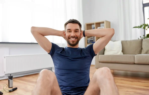 Hombre sonriente haciendo ejercicios abdominales en casa —  Fotos de Stock
