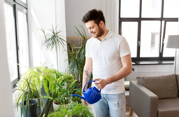 Hombre regar las plantas de interior en casa —  Fotos de Stock