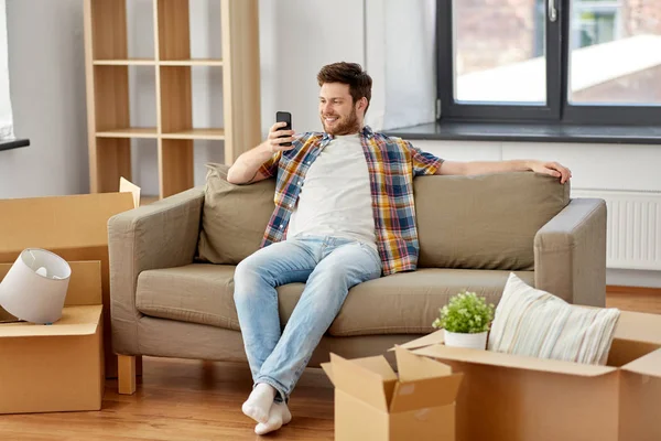 새 집 소파에 스마트폰과 박스가 있는 남자 — 스톡 사진
