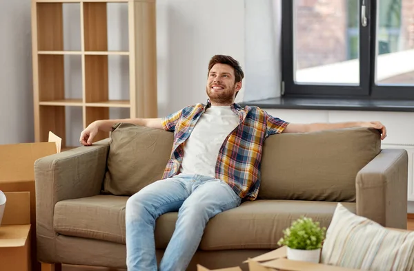 Boldog ember dobozokkal ül a kanapén az új otthon — Stock Fotó