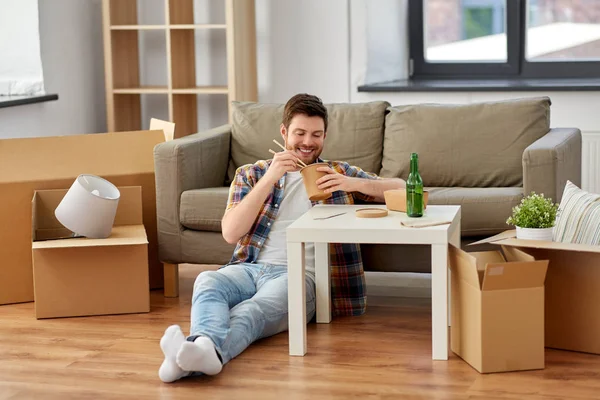 Lächelnder Mann isst im neuen Zuhause Essen zum Mitnehmen — Stockfoto