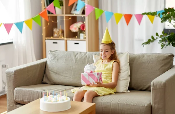 Happy girl in party hat with birthday gift at home — Stock Photo, Image