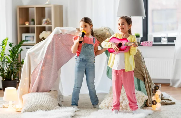 Meninas com guitarra e microfone jogando em casa — Fotografia de Stock