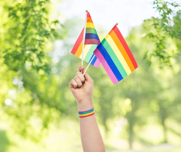 Hand with gay pride rainbow flags and wristband — Stock Photo, Image