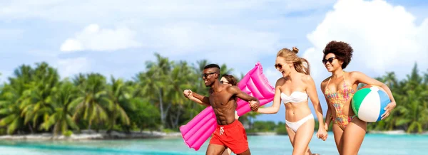 Amigos correr com bola de praia e colchão de natação — Fotografia de Stock