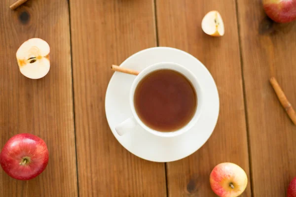 Чашка чая с яблоками и корицей на столе — стоковое фото