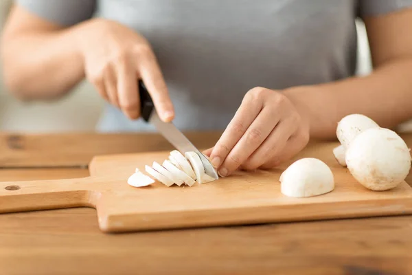 Woman cutting champignons by knife on board — Stock Photo, Image