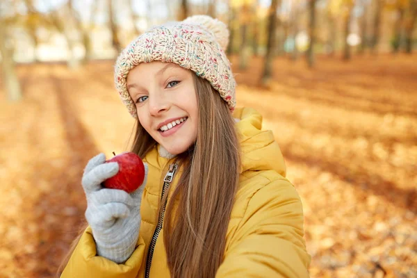 Menina feliz com maçã tomando selfie no parque de outono — Fotografia de Stock