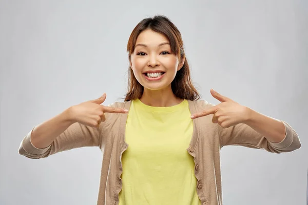 Gelukkig aziatische vrouw over grijs achtergrond — Stockfoto