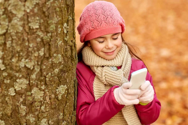 Dívka s chytrým telefonem v podzimním parku — Stock fotografie