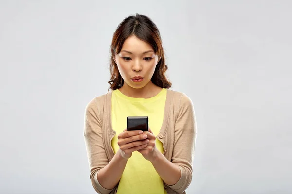 Şaşırmış Asyalı kadın akıllı telefon kullanıyor. — Stok fotoğraf