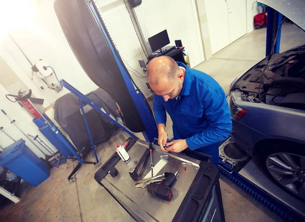 Szerelő férfi csavarkulccsal javítás autó műhelyben — Stock Fotó