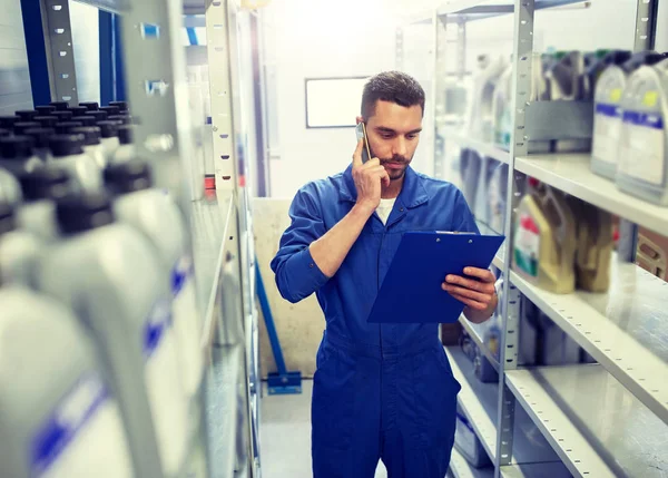 Mecánico automático llamando en el teléfono inteligente en el taller de automóviles — Foto de Stock