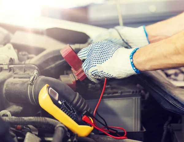 Auto mekaniker man med multimeter testa batteriet — Stockfoto