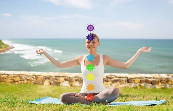 Vrouw doen yoga in lotus poseren met zeven chakra 's — Stockfoto