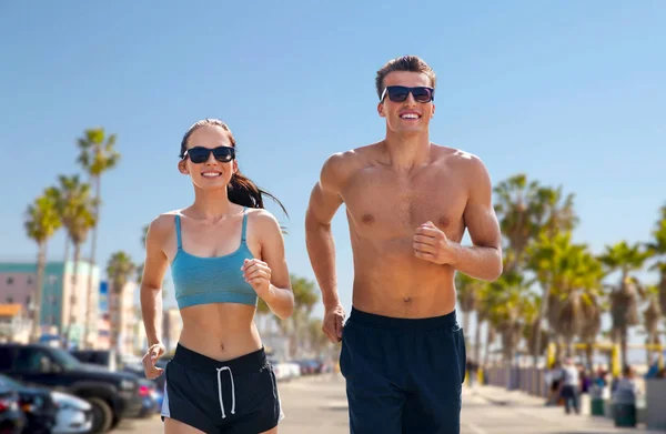 Пара в спортивной одежде бегает по пляжу — стоковое фото
