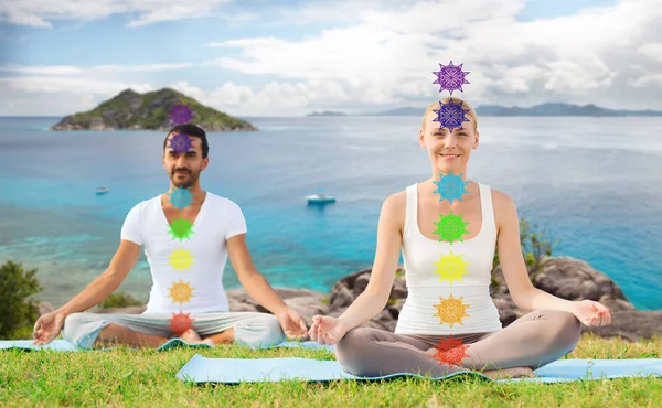Pareja haciendo yoga en pose de loto con siete chakras — Foto de Stock