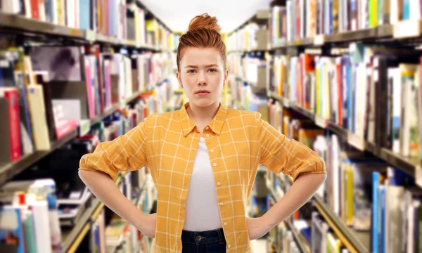 Missnöjd rödhårig student flicka på biblioteket — Stockfoto