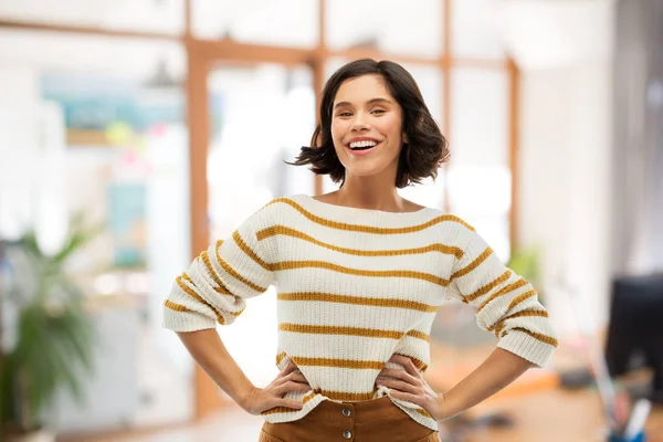 Glimlachende vrouw in trui met handen op heupen — Stockfoto