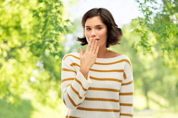 Woman covers mouth by hand over natural background — Stock Photo, Image