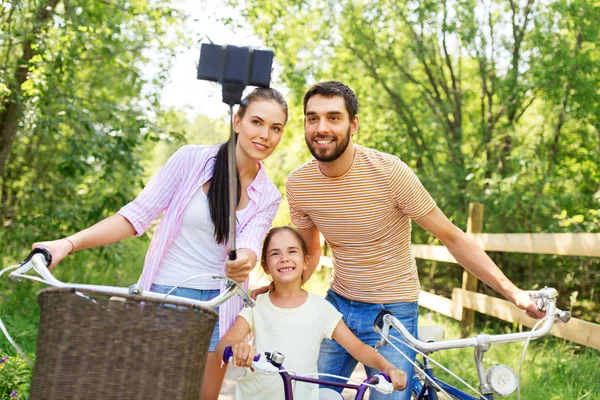 Família feliz com bicicletas tomando selfie no verão — Fotografia de Stock