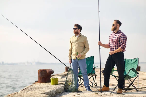 Amigos felizes com varas de pesca e cerveja no cais — Fotografia de Stock