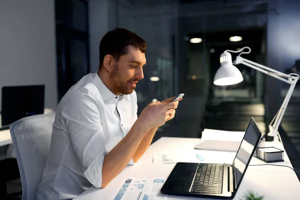 Geschäftsmann mit Smartphone und Computer im Büro — Stockfoto