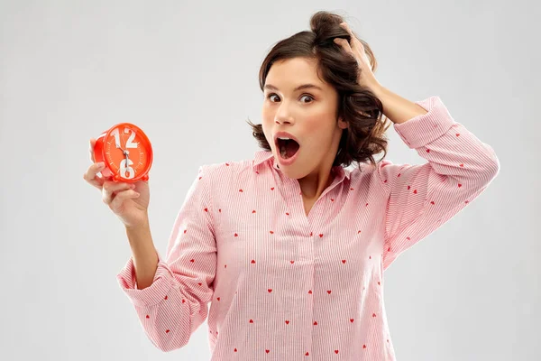 Shocked young woman in pajama with alarm clock — Stock Photo, Image