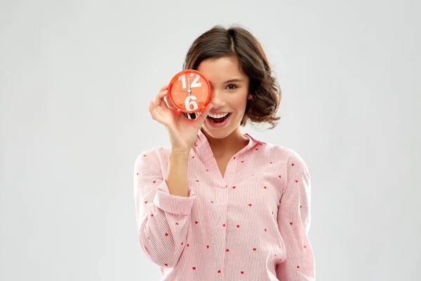 Glückliche junge Frau im Pyjama mit Wecker — Stockfoto