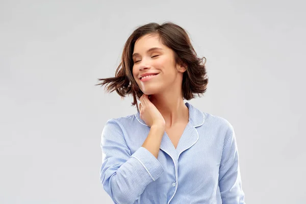 Glückliche junge Frau im Pyjama vor grauem Hintergrund — Stockfoto