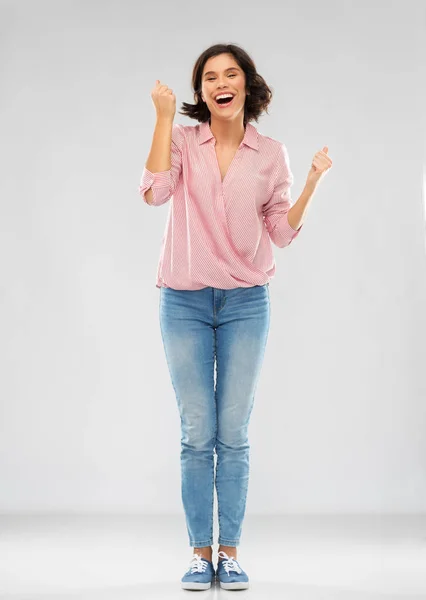 Mujer joven en camisa y jeans celebrando el éxito — Foto de Stock