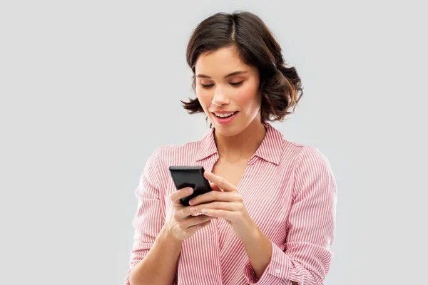 Mujer joven con camisa a rayas usando smartphone — Foto de Stock