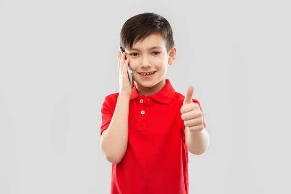Leende pojke i röd t-shirt ringer på smartphone — Stockfoto