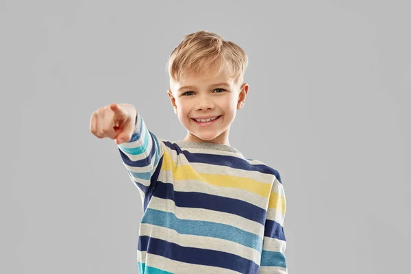 Usmívající se chlapec v pruhovaném svetru ukazující prstem — Stock fotografie