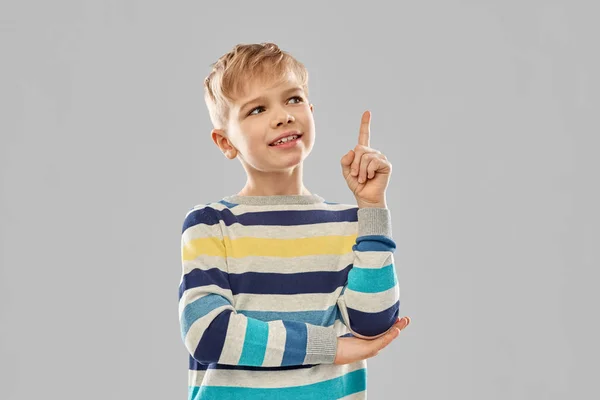 Мальчик в полосатом свитере показывает пальцем вверх — стоковое фото