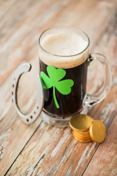 Shamrock op glas bier, hoefijzer en munten — Stockfoto