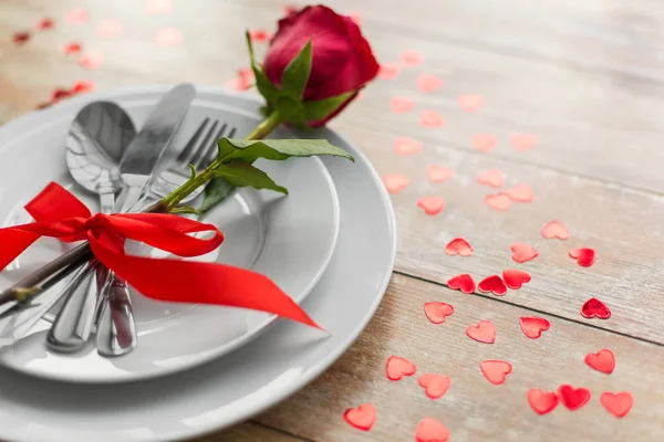 Close up of red rose flower on set of dishes — Stock Photo, Image