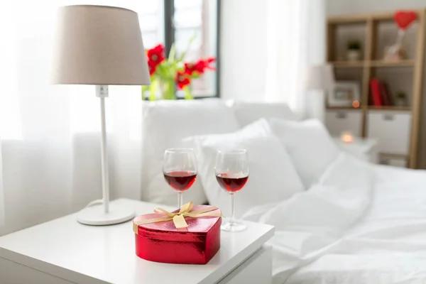 Regalo e due bicchieri di vino in camera da letto a casa — Foto Stock