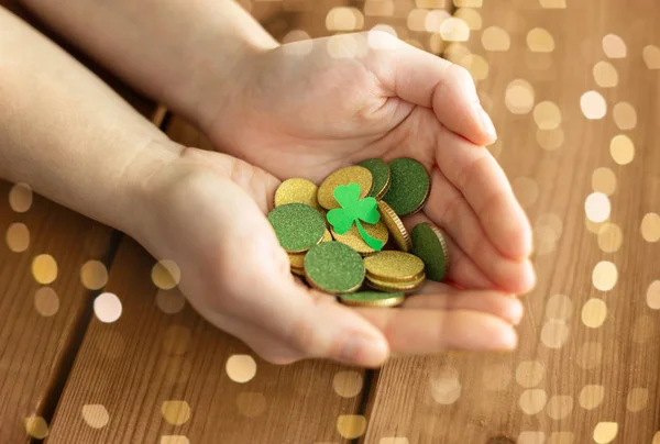 Manos con monedas de oro y hoja de trébol — Foto de Stock