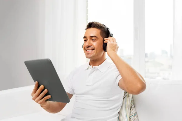 Sorrindo homem com tablet pc e fones de ouvido em casa — Fotografia de Stock