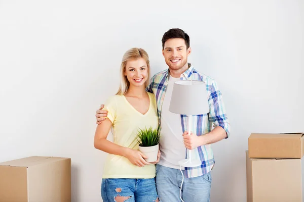 Pareja con flor y lámpara mudándose a un nuevo hogar — Foto de Stock